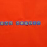 Blue letter blocks spelling 'Bad Credit' on an orange background.
