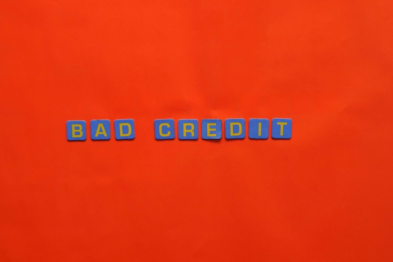Blue letter blocks spelling 'Bad Credit' on an orange background.